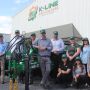 Twelve staff members standing in front of a K-Line Ag machine in the carpark at the k-Line Cowra factory. The K-Line Ag name and logo is printed on the front of the building.